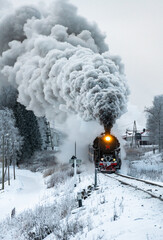 Retro steam locomotive in snowy winter landscape.