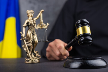 Judge with gavel and Themis Lady Justice against flag of Ukraine and dark background