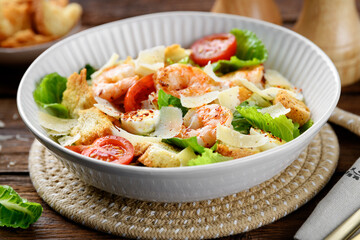 Classic Italian Caesar Salad with Shrimp on wooden background