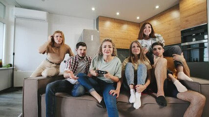 Group of friends enjoying a video game night in a modern living room while intensely focused on gameplay and sharing laughter