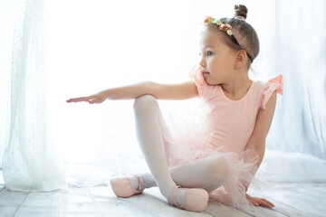 Little girl in tutu ballet costume with flowers in her hair exercising on the floor © Pawparazzi
