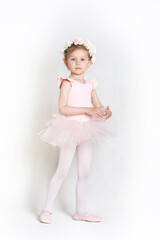 Cute little girl wearing tutu skirt in a ballet lesson, white background