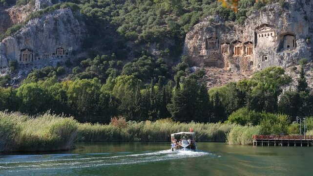 Lycian King Tombs in Kaunos Ancient City. Tourist boat on the Dalyan canal. Ortaca district, Mugla province, Turkey country - 4k video 