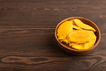 Dried Mango in wooden bowl on brown wooden. Side view, copy space