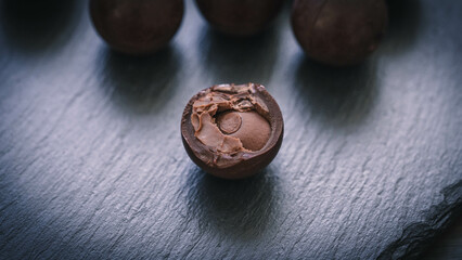 Edle Schokoladenkugeln auf schwarzer Schieferplatte