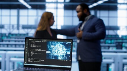 Fototapeta premium Close up of laptop with AI technology used to sustain data center hardware. Focus on notebook used by server room programmers in background using artificial intelligence tech, camera A