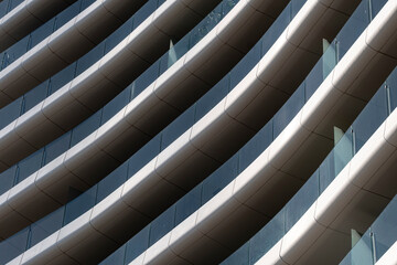 Abstract view of modern building facade with curved balconies and glass railings, emphasizing contemporary design.