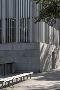 Minimalist concrete facade with vertical lines and shadows creating geometric patterns, highlighting modern urban architecture.