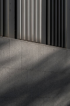 Close-up of a concrete facade with soft diagonal shadows creating subtle geometric patterns in urban architecture.