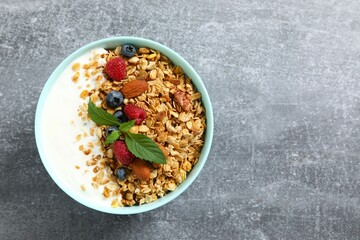 Delicious granola with berries and yogurt on a gray background