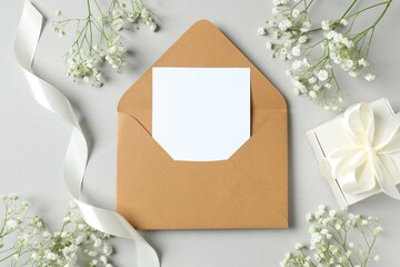 Top view photo with gypsophila flowers, paper envelope and gift box on gray background 