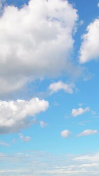 Big white clouds slowly floating across the blue sky. Background with a calm summer sky.