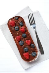 Delicious tiramisu cake with berries on table