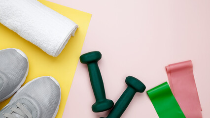 Fitness accessories including sneakers, dumbbells, resistance bands, and a towel on pastel backgrounds