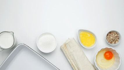 Baking Crinkle Cake. Near baking dish with ingredients, phyllo dough, egg, butter, nuts, and milk