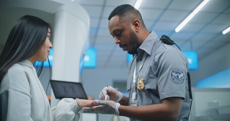 Airport Terminal: African American Security Officer Conducts TSA Hand Swab Screening with Brush to Asian Woman for Flight. ETD Procedure to Identify Traces of Explosive Materials. Medium Close Up.