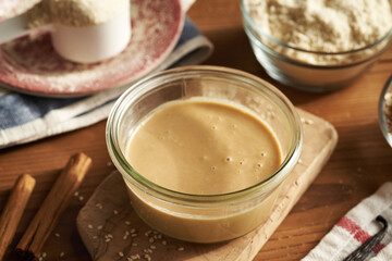 A jar of sesame tahini, whey protein powder and cinnamon - ingredients for homemade no-bake protein bars