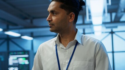 System administrator walks in data center used for managing gear energy consumption, working on tablet. Close up of IT specialist using device in workspace used for automation in server room, camera A