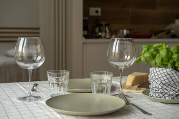 empty plates on the table, spring cozy home table setting with glasses and fresh basil on light tablecloth. copy space. background for menu