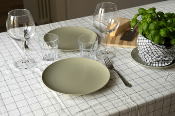 empty plates on the table, spring cozy home table setting with glasses and fresh basil on light tablecloth. copy space. background for menu
