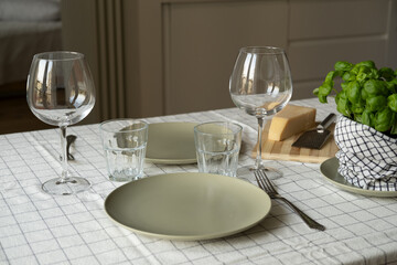 empty plates on the table, spring cozy home table setting with glasses and fresh basil on light tablecloth. copy space. background for menu