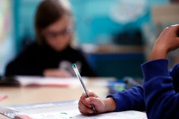 Primary school child writing on a desk during a lesson.  France.