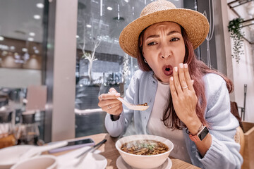 Tourist enjoying traditional food in a chinese restaurant, surprised by the taste of hot and spicy...