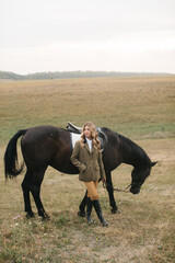 Obraz premium Elegant Woman Standing Outdoor with Horse in Scenic Countryside Meadow