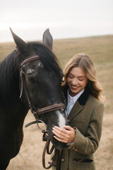 Obraz premium Young Woman Smiling Beside Black Horse in Serene Outdoor Setting