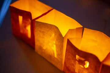 cardboard boxes illuminated with candles inside with letters cut out with the construction of the word happy birthday