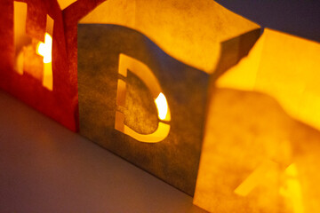 cardboard boxes illuminated with candles inside with letters cut out with the construction of the word happy birthday