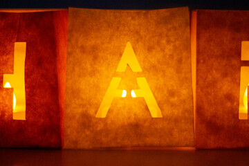 cardboard boxes illuminated with candles inside with letters cut out with the construction of the word happy birthday