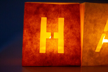 cardboard boxes illuminated with candles inside with letters cut out with the construction of the word happy birthday