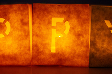 cardboard boxes illuminated with candles inside with letters cut out with the construction of the word happy birthday
