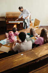 Music Professor Teaching Students in Classroom With Piano