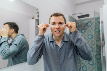 Man removing eye patches on his face. Wrinkles and face home care for men.