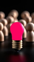 A vibrant pink light bulb stands out among wooden figurines, symbolizing creativity and ideas.