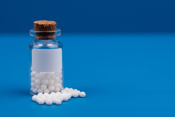 Homeopathy alternative medicine concept with classic homeopathic globules on a blue background. Emphasizing natural healing, holistic health, and eco-friendly remedies in alternative medicine.