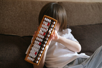 Little preschool boy toddler is doing simple math exercises with abacus scores. Mental arithmetic.