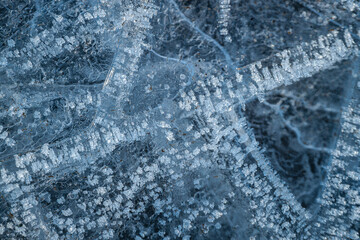 Close-up of intricate ice formations with frozen air bubbles and crystal-like structures. The detailed patterns and textures create a mesmerizing abstract winter scene.
