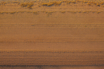 Close-up of textured sand with parallel ridges created by wind and water. The golden sunlight...