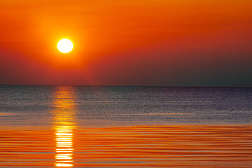 A mesmerizing sunset over the ocean, casting golden and orange hues across the sky and water. The...