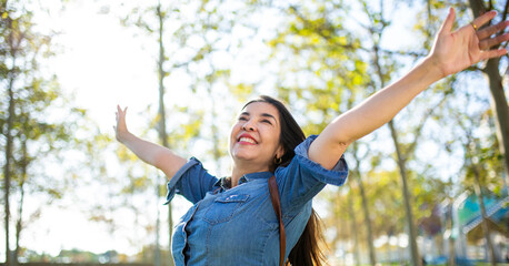 Happy woman in a denim shirt enjoying nature with arms wide open