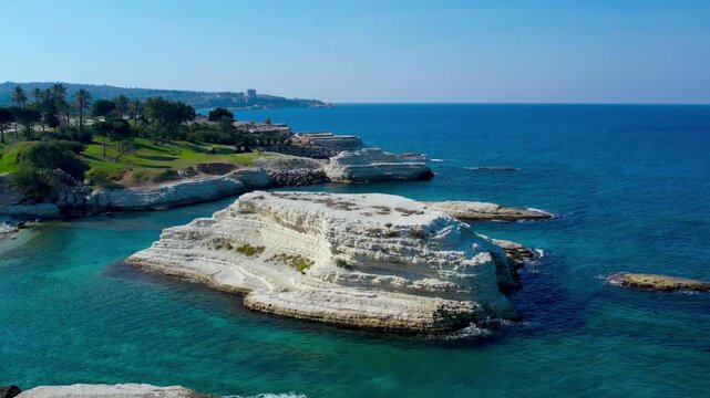 Aerial shot of crashing ocean waves and rocky shores, showcasing the dynamic movement of the water.