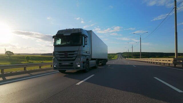 Truck with white cargo semi-trailer driving on highway, logistics and delivery of goods by freight transportation.
