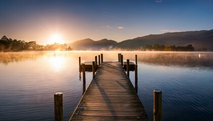 Fototapeta premium beautiful misty sunrise with wooden jetty at derwentwater in the lake district uk