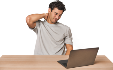 Hispanic young man working on laptop suffering neck pain due to sedentary lifestyle.