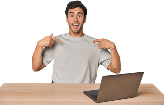 Hispanic young man working on laptop surprised pointing with finger, smiling broadly.