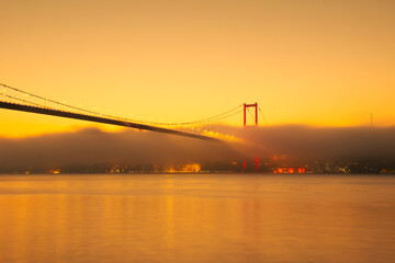 View of July 15 Martyrs Bridge (Bosphorus Bridge) with seagull and sunrise in fog clouds. Fishing boats in the foggy Bosphorus.