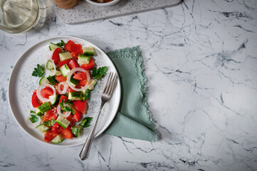Fresh salad with tomatoes, cucumbers, onions, herbs, butter and sesame seeds. Delicious snack. Salad with tomatoes.